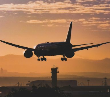 Silhouette of aircraft landing at sunset